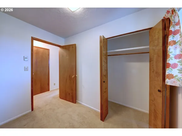 a view of an empty room with closet and a window