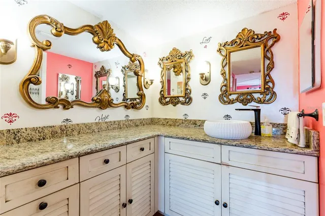 a bathroom with a granite countertop sink and a mirror