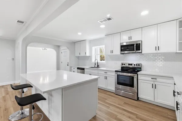 a kitchen with stainless steel appliances a stove sink microwave and cabinets