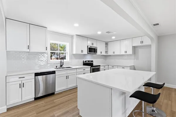 a kitchen with a sink a stove a refrigerator and white cabinets