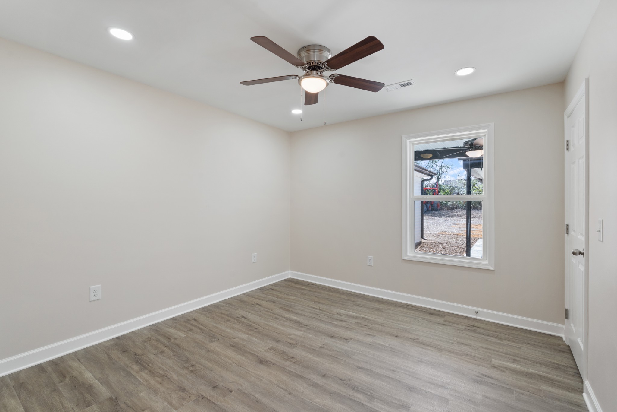 654 West Main Street Hohenwald, TN 38462 - Photo 21 of 33 an empty room with wooden floor ceiling fan and windows