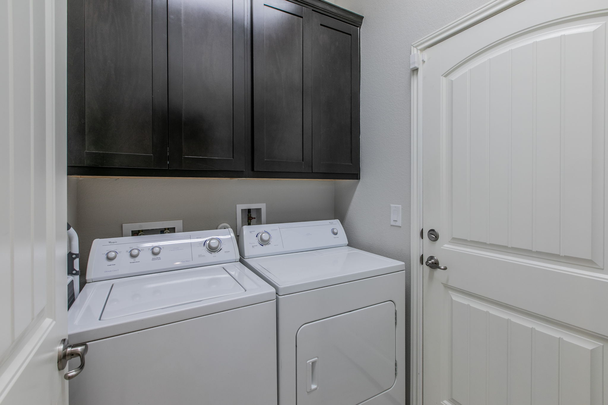 231 Simon Kyle, TX 78640 - Photo 23 of 29 Dedicated laundry area featuring dark wood-finish cabinetry, light gray walls, and white appliances