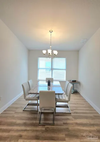 a view of a dining room with furniture a chandelier and wooden floor
