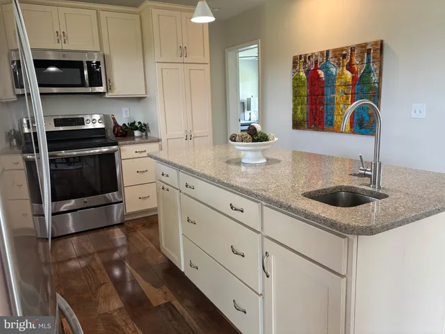 a kitchen with stainless steel appliances granite countertop a refrigerator stove a sink dishwasher and a refrigerator with wooden floor