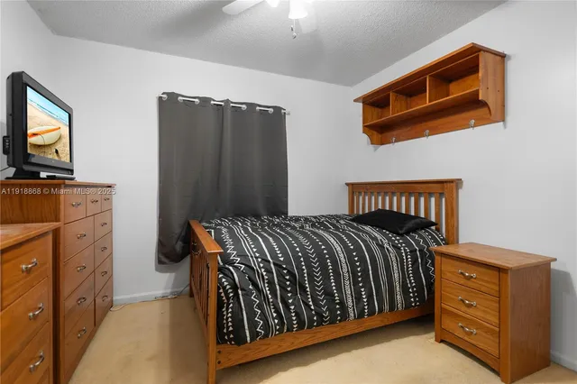 a bedroom with a bed and flat tv screen on the dresser