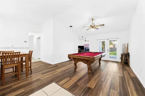 a room with wooden floors pool table and chairs