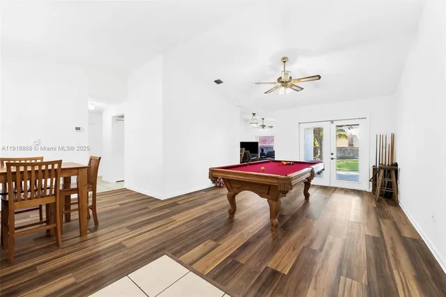 a room with wooden floors pool table and chairs