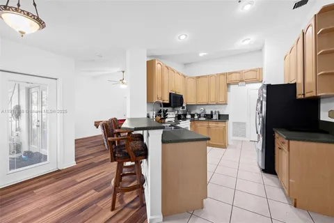 a kitchen with granite countertop a refrigerator a stove top oven a sink dishwasher and white cabinets with wooden floor