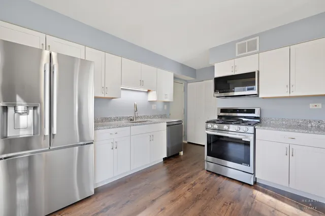 a kitchen with granite countertop a refrigerator stove and wooden floor