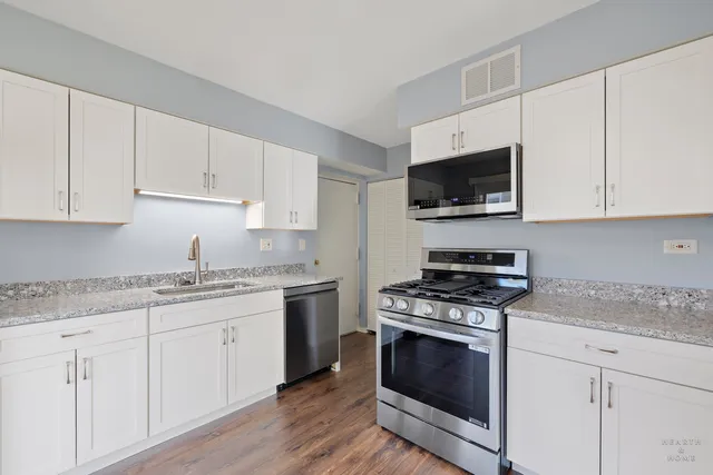 a kitchen with granite countertop a stove a sink and wooden floor