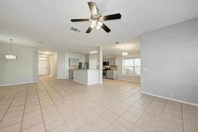 a view of an empty room with kitchen and a fireplace