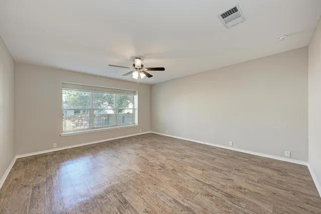 a view of empty room with wooden floor and ceiling fan