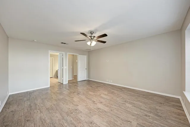a view of an empty room with wooden floor and a window