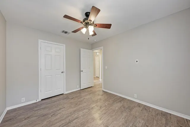 a view of an empty room with window and chandelier fan