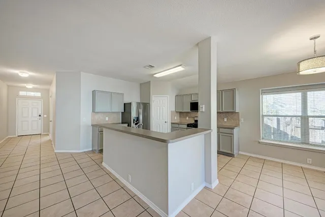 a kitchen with stainless steel appliances a stove top oven a sink a refrigerator and white cabinets