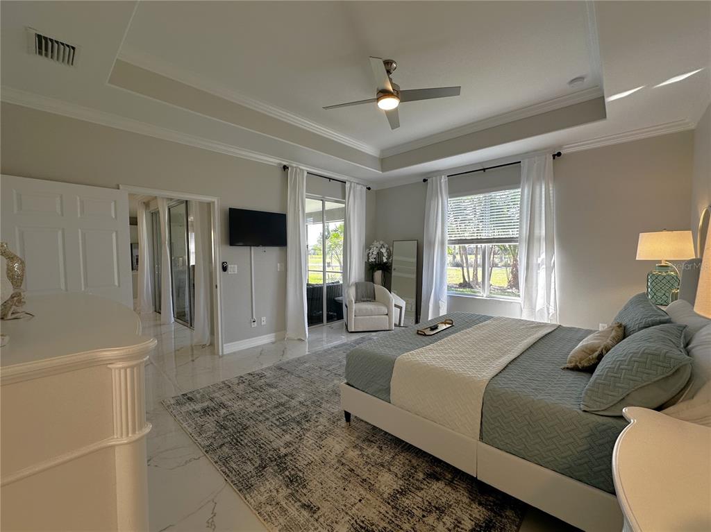 25191 Keygrass Court Punta Gorda, FL 33955 - Photo 19 of 66 a spacious bedroom with a bed and a chandelier