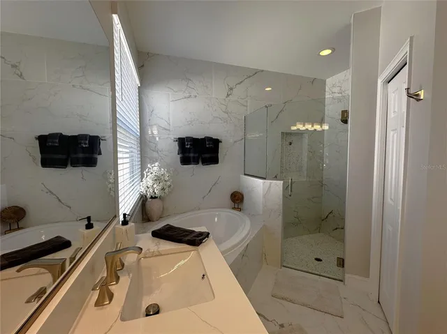 a bathroom with a tub a sink and a large mirror