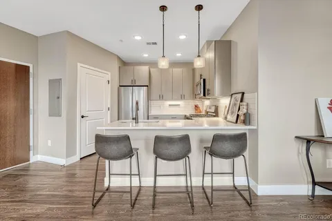 a kitchen with kitchen island granite countertop a table chairs refrigerator and microwave