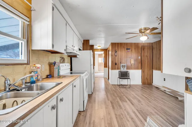 a kitchen with a sink dishwasher a refrigerator and cabinets with wooden floor