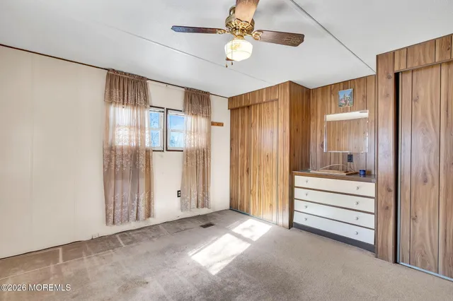 a view of a livingroom with a chandelier fan and windows
