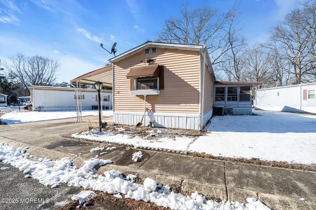 a view of white house with a yard covered with snow and wooden fence