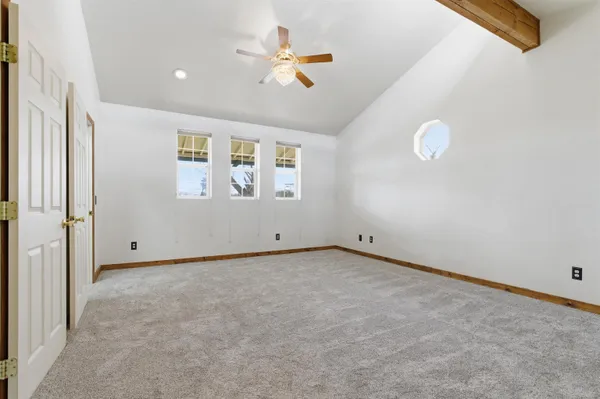 an empty room with a ceiling fan and window