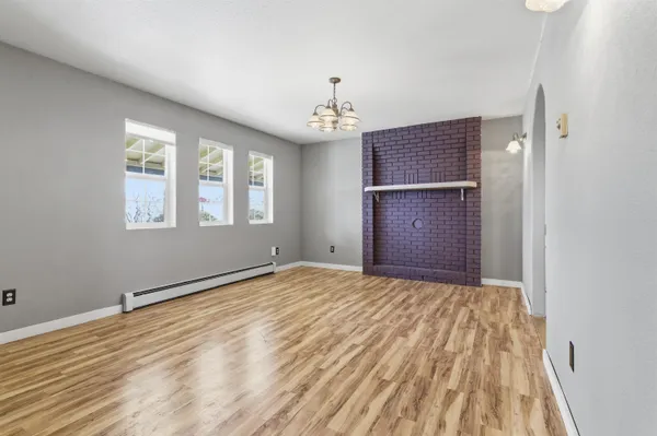 a view of an empty room with wooden floor and windows