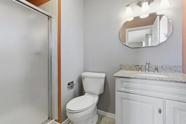 a bathroom with a granite countertop toilet sink mirror and vanity