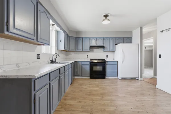a kitchen with granite countertop a refrigerator a sink and a stove
