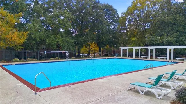 a view of swimming pool with lawn chairs and plants