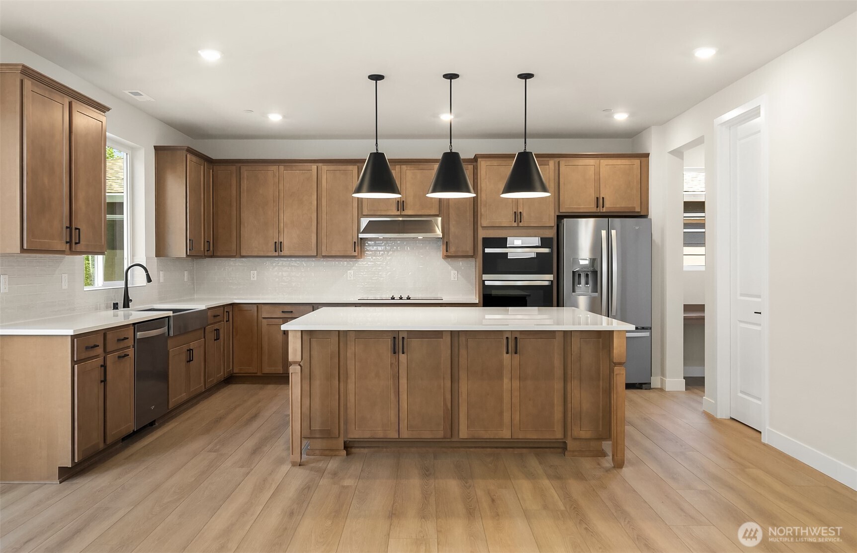 23361 Arbors Terrace Road Northeast, Unit 21 Kingston, WA 98346 - Photo 3 of 19 a kitchen with stainless steel appliances kitchen island granite countertop a sink a stove a refrigerator and island with wooden floor