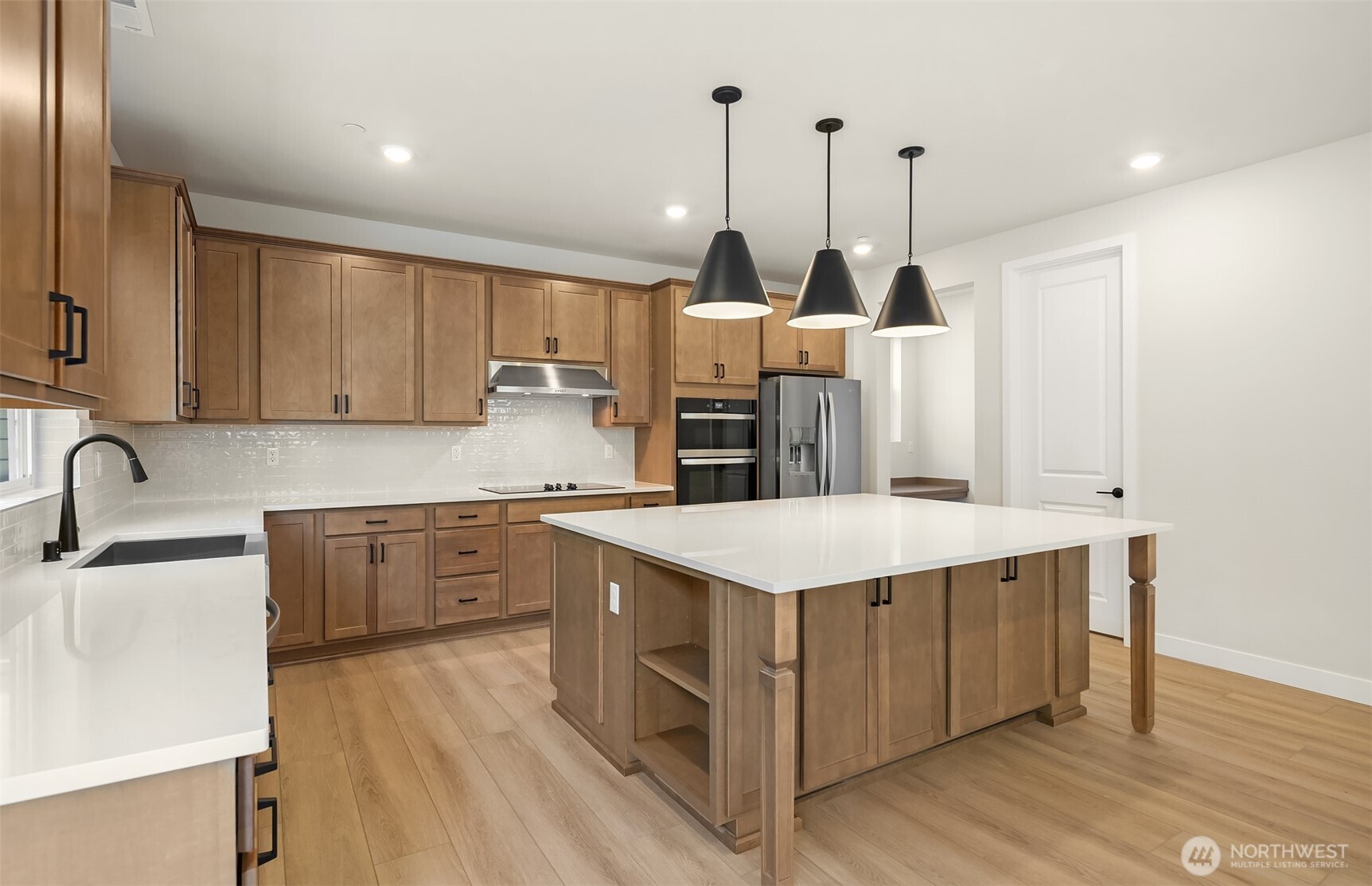 23361 Arbors Terrace Road Northeast, Unit 21 Kingston, WA 98346 - Photo 4 of 19 a kitchen with stainless steel appliances kitchen island granite countertop a sink a stove and a wooden floors