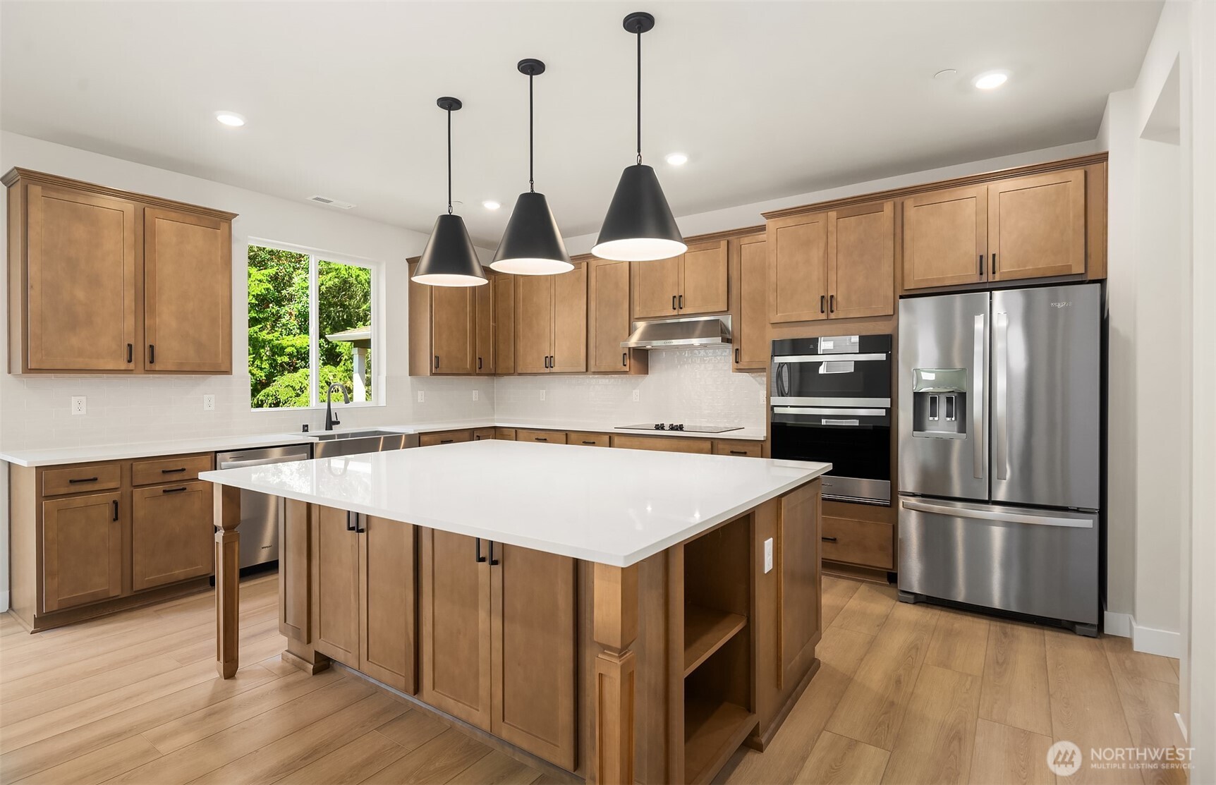23361 Arbors Terrace Road Northeast, Unit 21 Kingston, WA 98346 - Photo 5 of 19 a kitchen with kitchen island a stove a sink a center island and a wooden floor