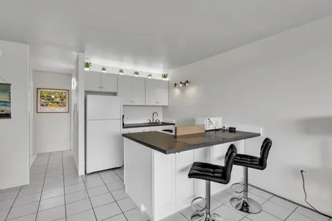 a kitchen with stainless steel appliances kitchen island granite countertop a sink and a refrigerator
