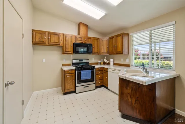 a kitchen with kitchen island granite countertop a sink appliances cabinets and a counter top space