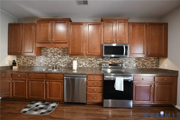a kitchen with stainless steel appliances granite countertop wooden cabinets a stove top oven a sink and dishwasher