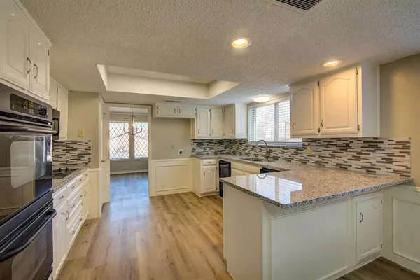 a kitchen with kitchen island granite countertop a sink cabinets and stainless steel appliances