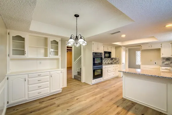 a view of a kitchen with stainless steel appliances granite countertop a refrigerator and a stove top oven