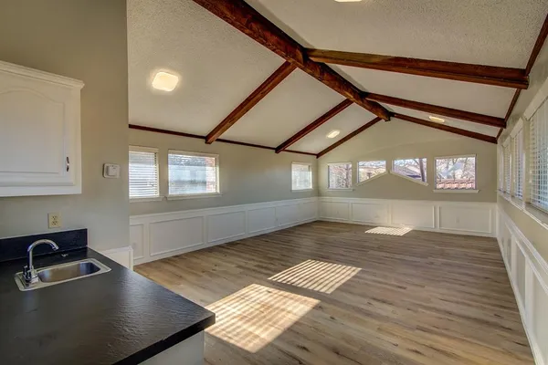 a view of an empty room with window and wooden floor