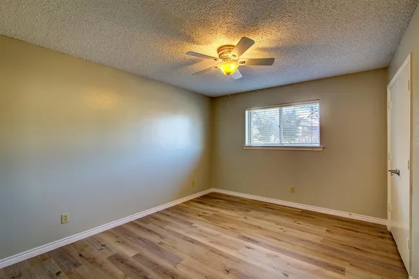 a view of an empty room with a window and wooden floor