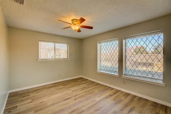 a view of an empty room with a window and wooden floor