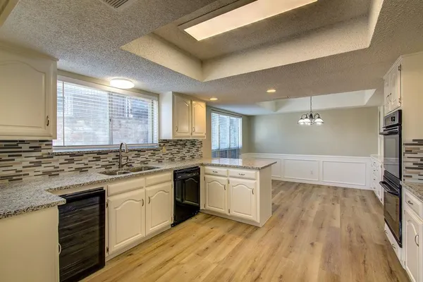 a large kitchen with cabinets wooden floor and stainless steel appliances