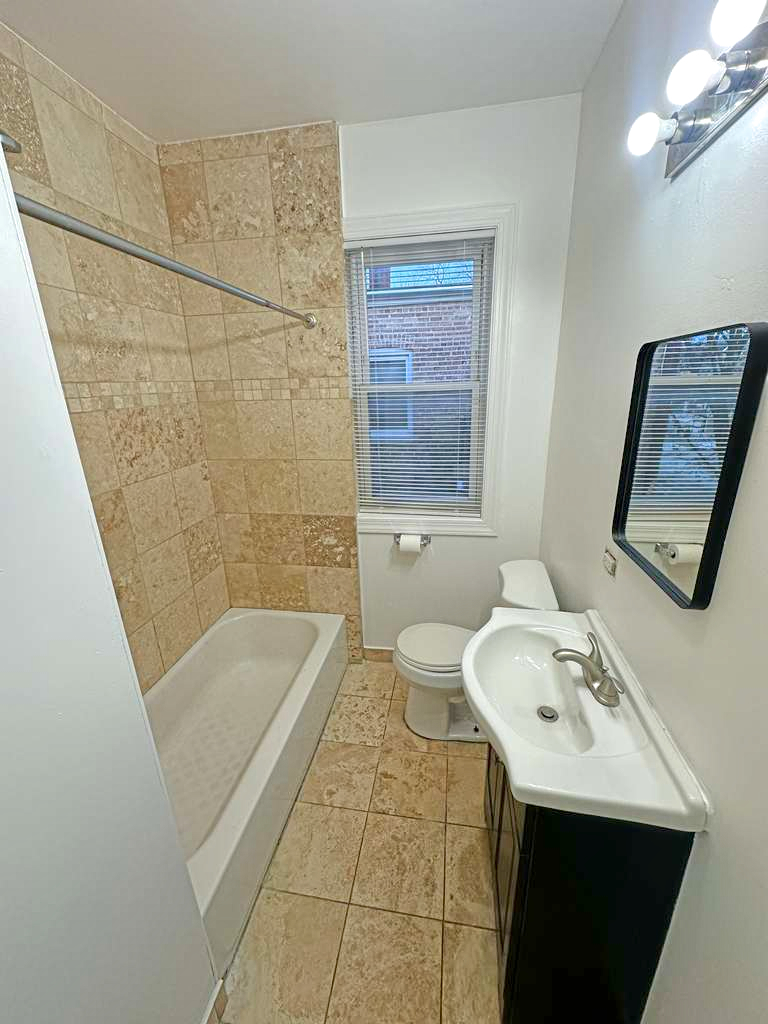 5145 West Ferdinand Street, Unit 2 Chicago, IL 60644 - Photo 13 of 13 a bathroom with a sink a toilet a mirror and shower