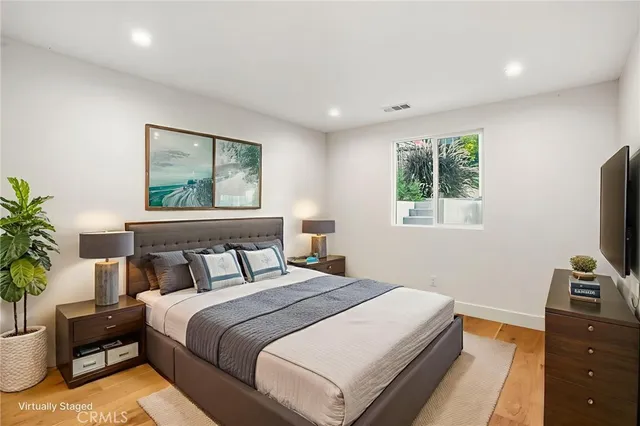 a bedroom with a bed and a flat tv screen on a dresser