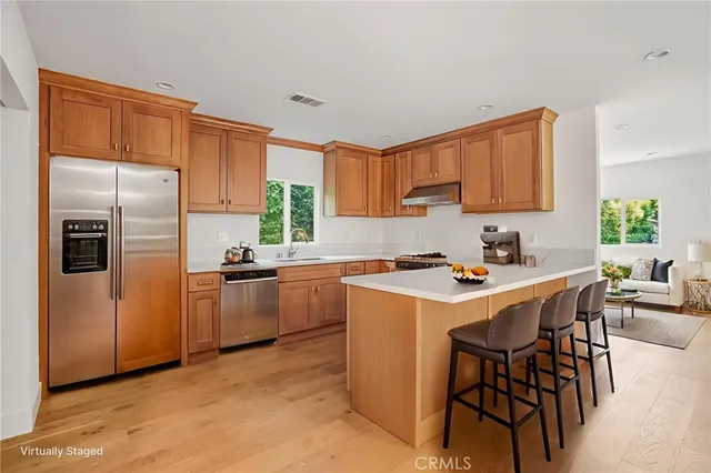 a kitchen with stainless steel appliances a sink a stove a refrigerator cabinets and a dining table