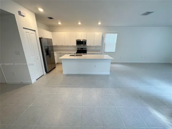 a large kitchen with stainless steel appliances a refrigerator and a stove top oven