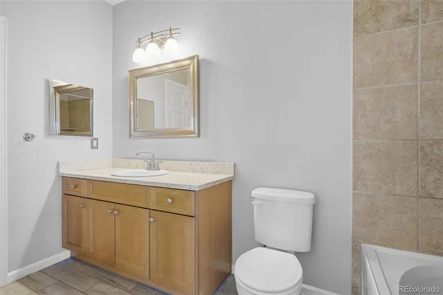 a bathroom with a toilet sink vanity and mirror