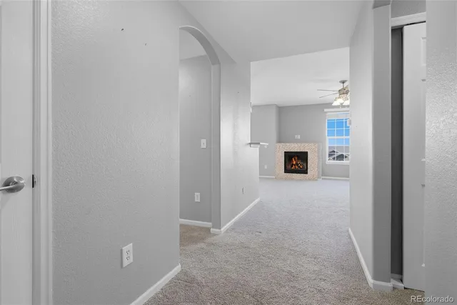 a view of a hallway to an empty room and fire place