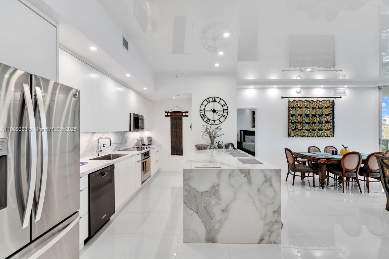 3131 Northeast 188th Street, Unit 21004 Aventura, FL 33180 - Photo 5 of 53 a large kitchen with kitchen island a refrigerator and a dining table
