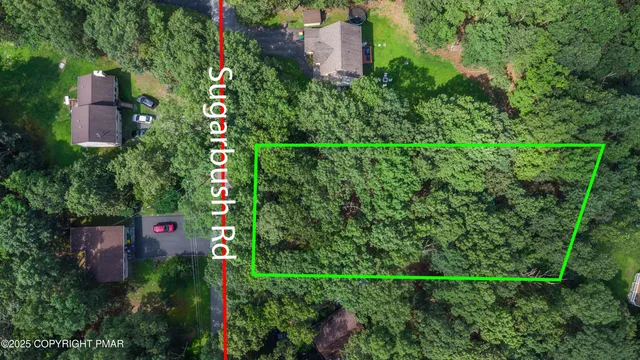 an aerial view of residential house with outdoor space and trees all around